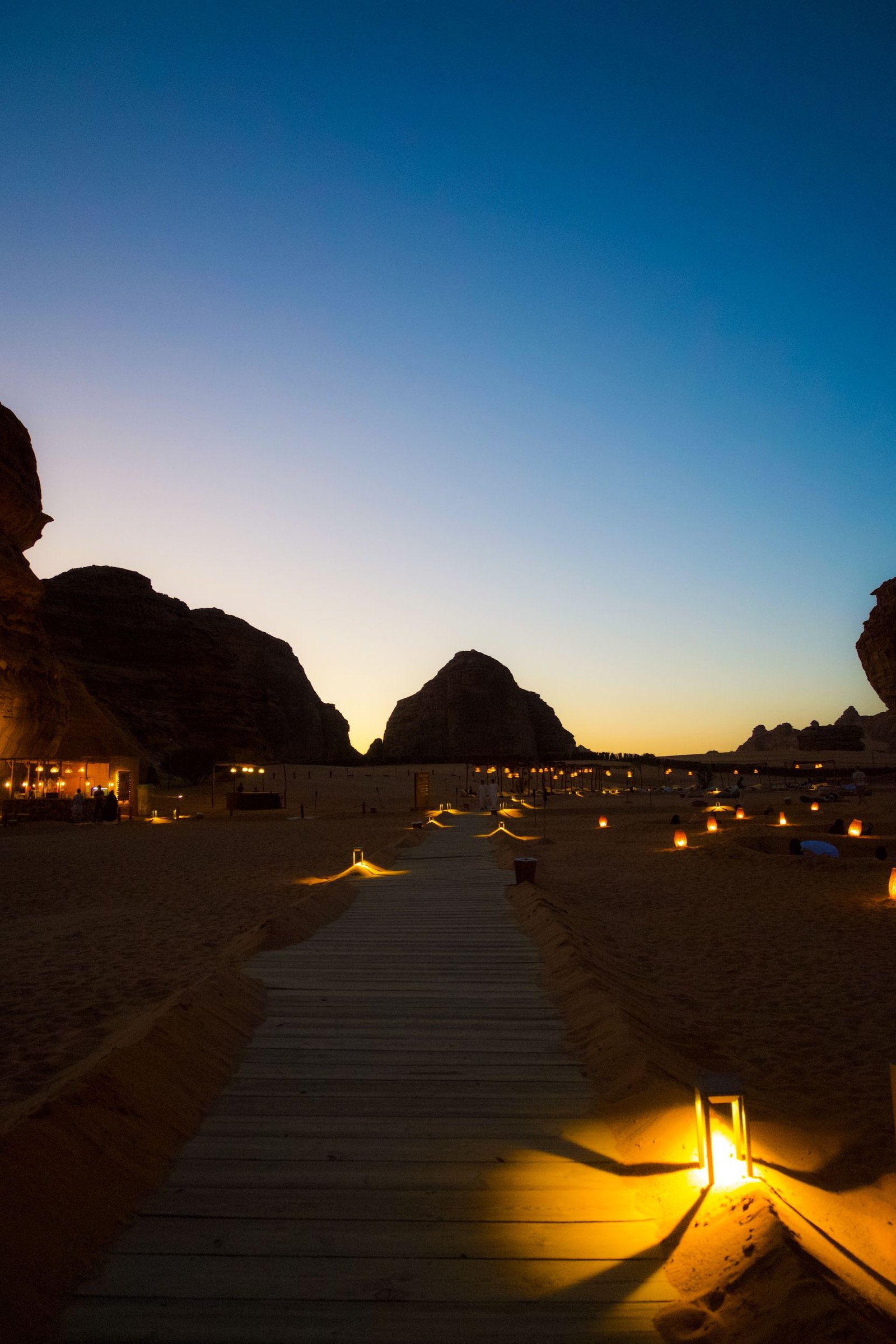 A lantern-lit path between sandstone outcrops in AlUla at dusk