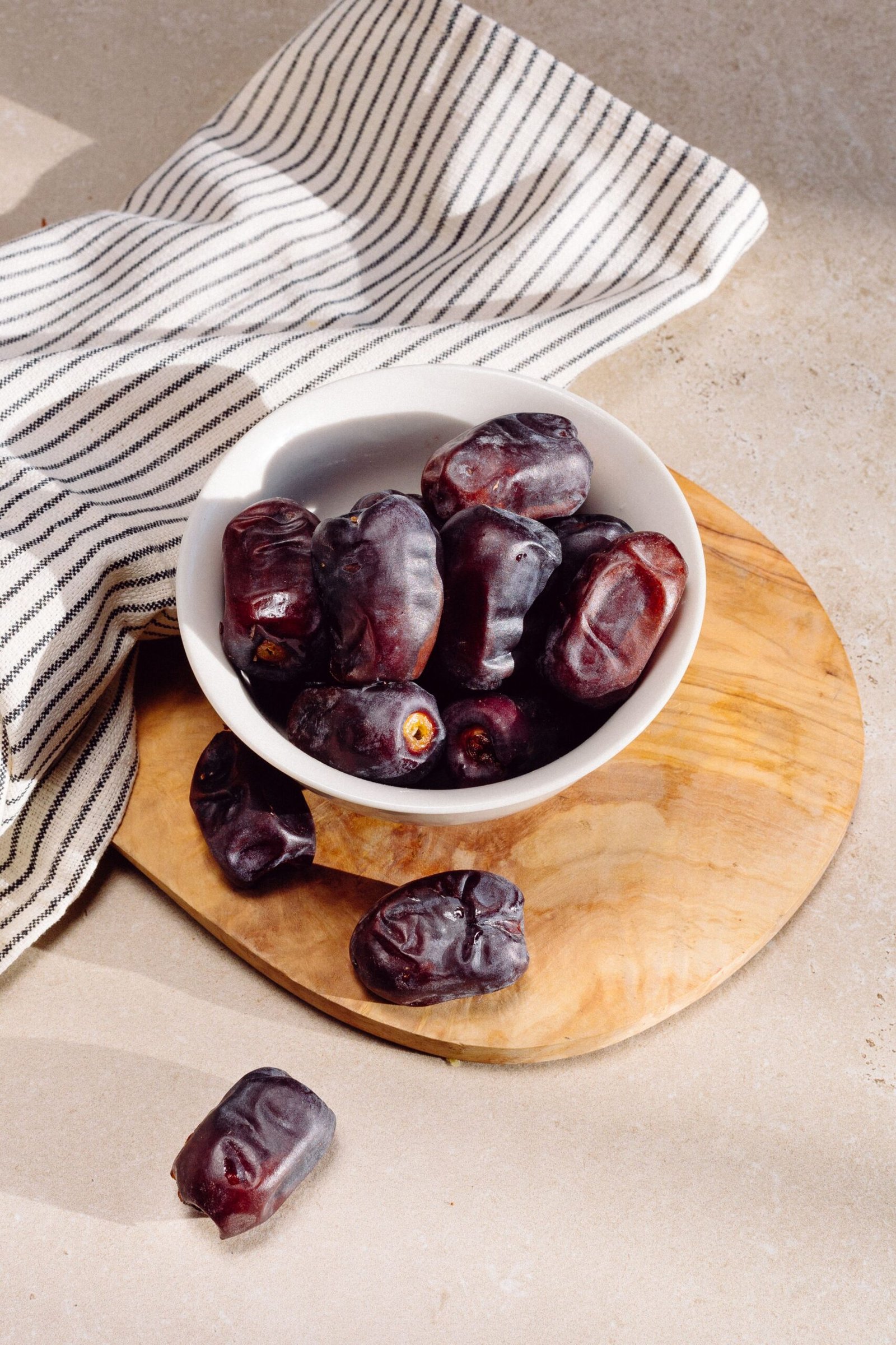 Dried dates in a wooden bowl beside fresh roses