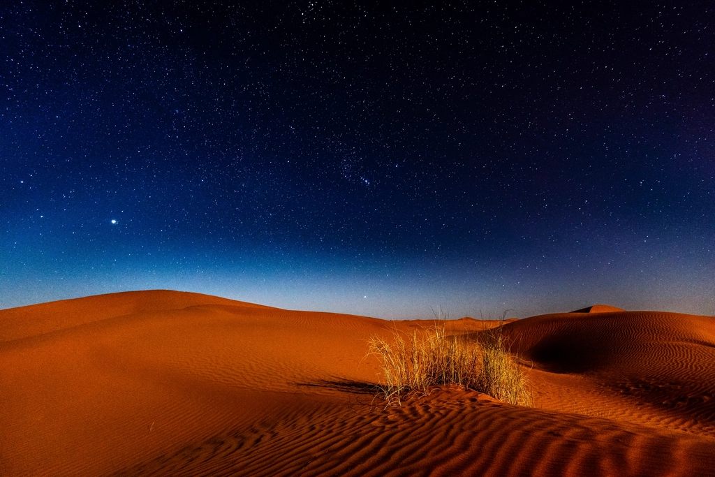 A starry night sky above desert dunes