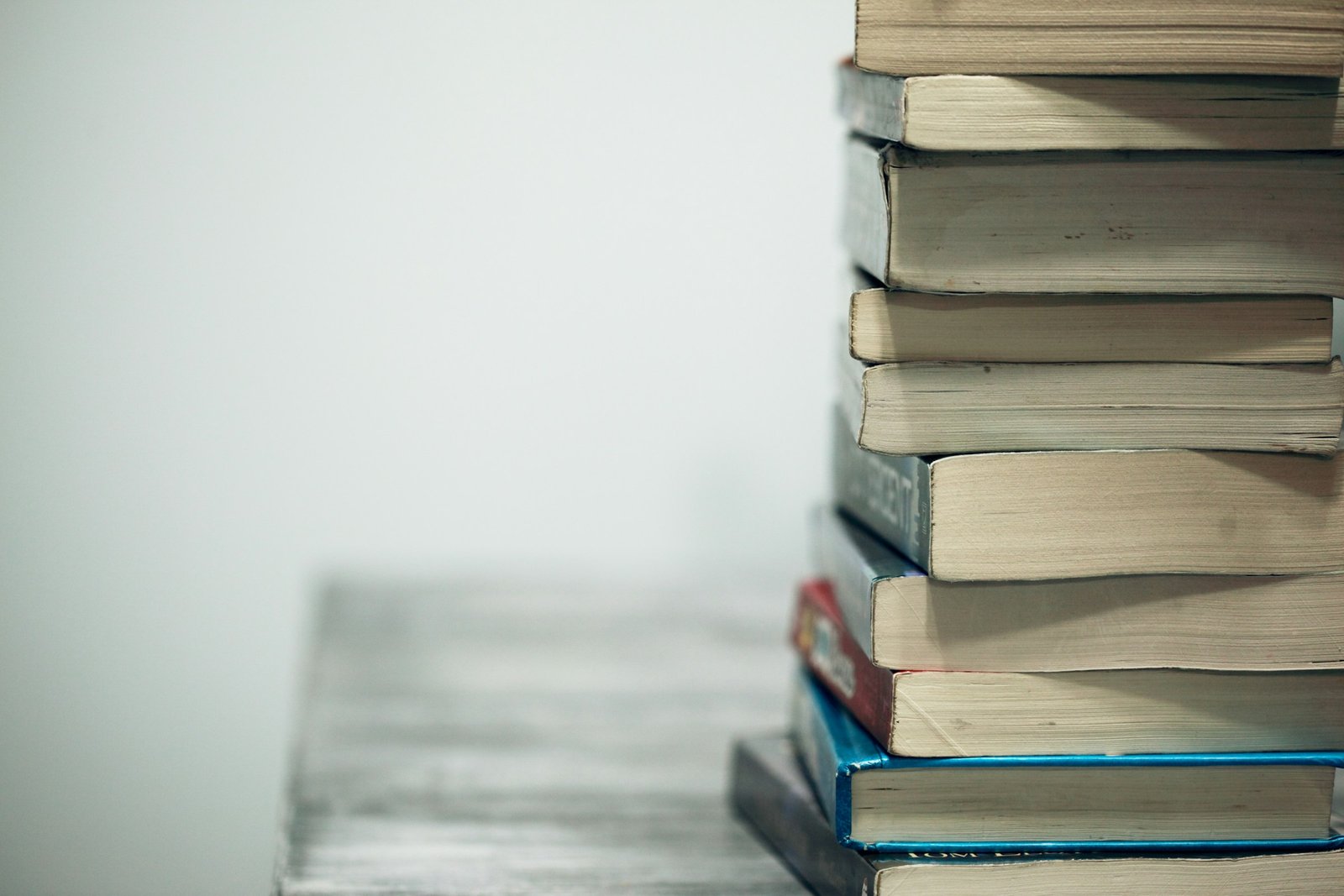 A stack of hardback novels on a wooden table
