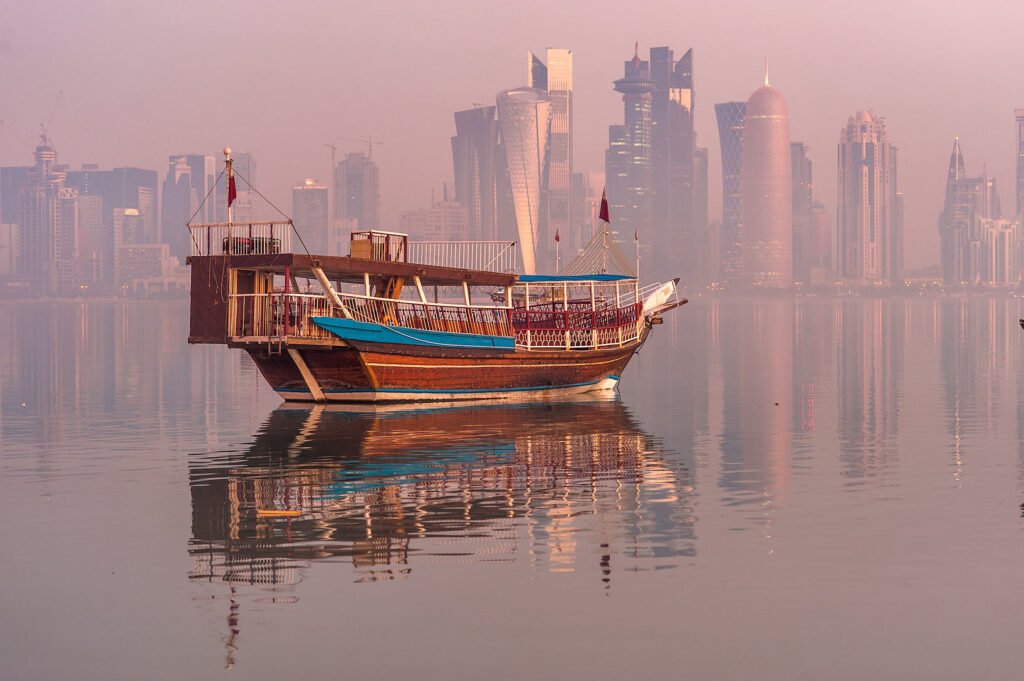A wooden dhow on Doha Bay with the West Bay towers behind