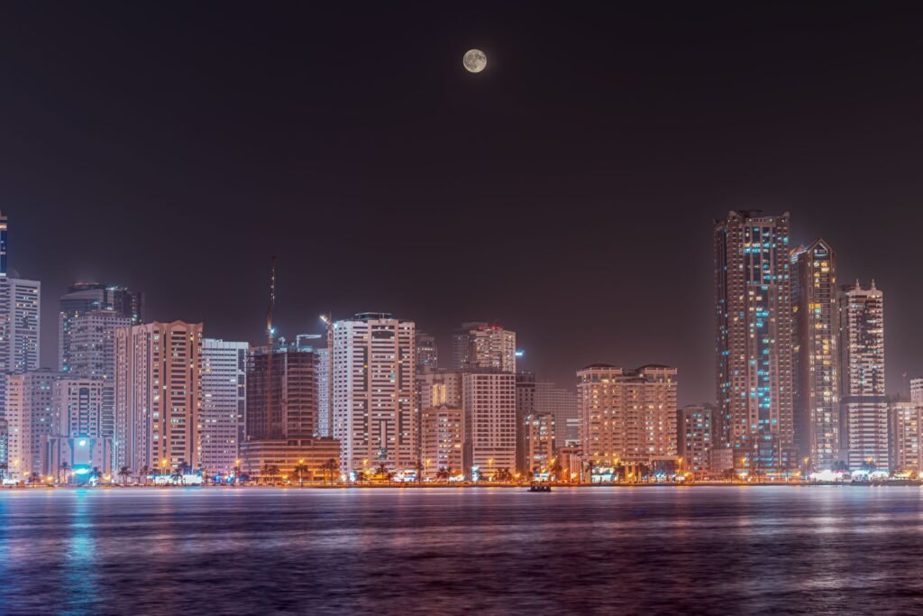 The Sharjah waterfront at dusk, with lights reflected in the water