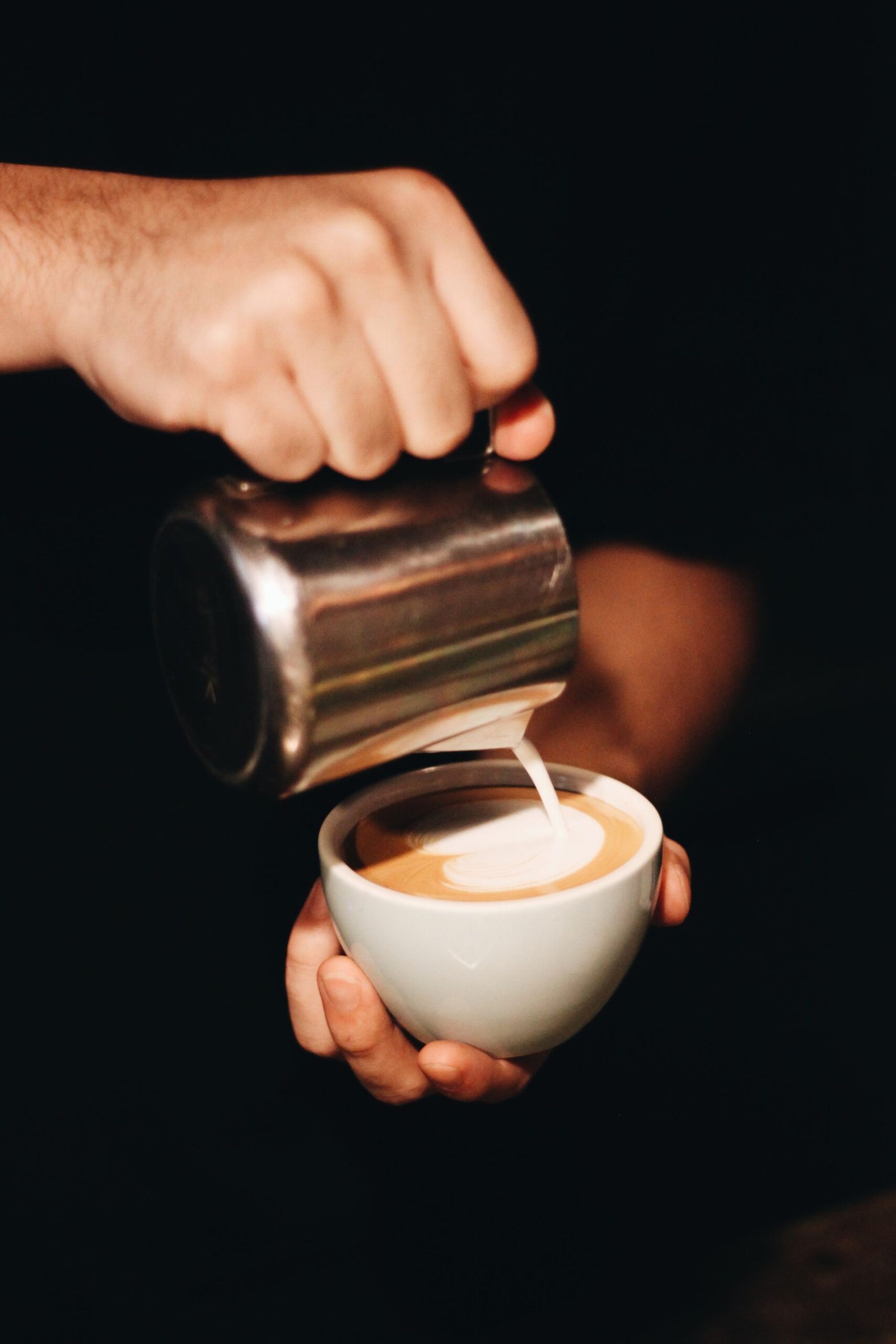 A barista pouring latte art into a cup