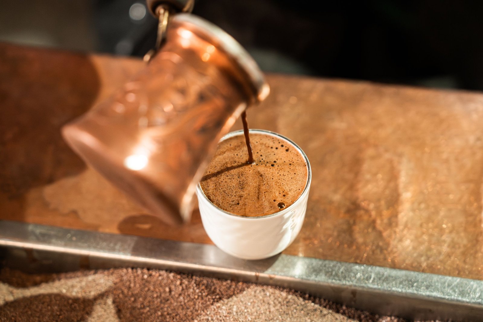 Arabic coffee being poured from a dallah into a small cup
