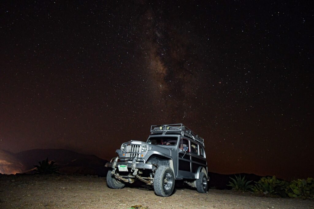 An off-road vehicle parked beside a desert camp at dusk