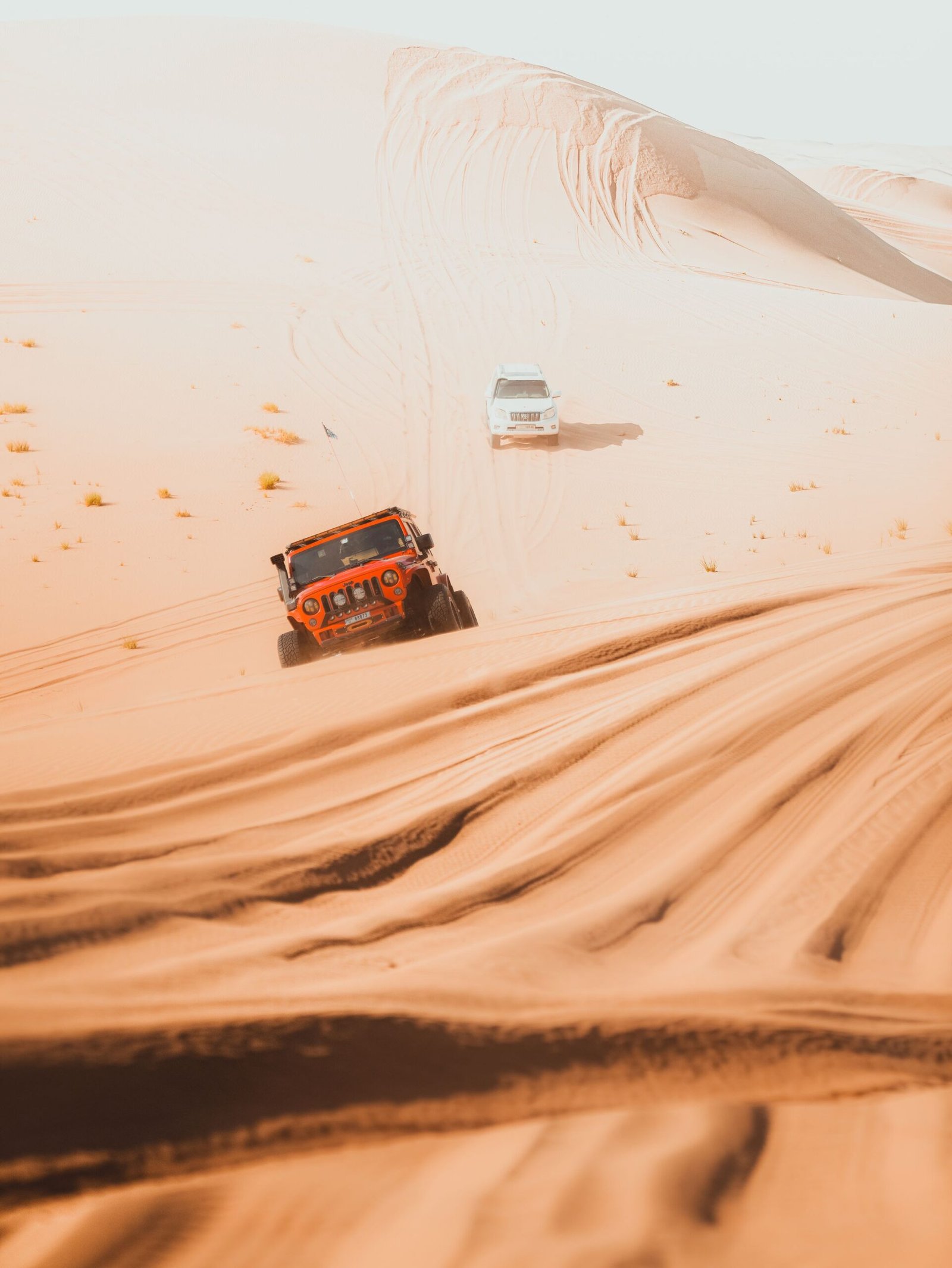 A four-wheel-drive vehicle climbing a sand dune in the desert