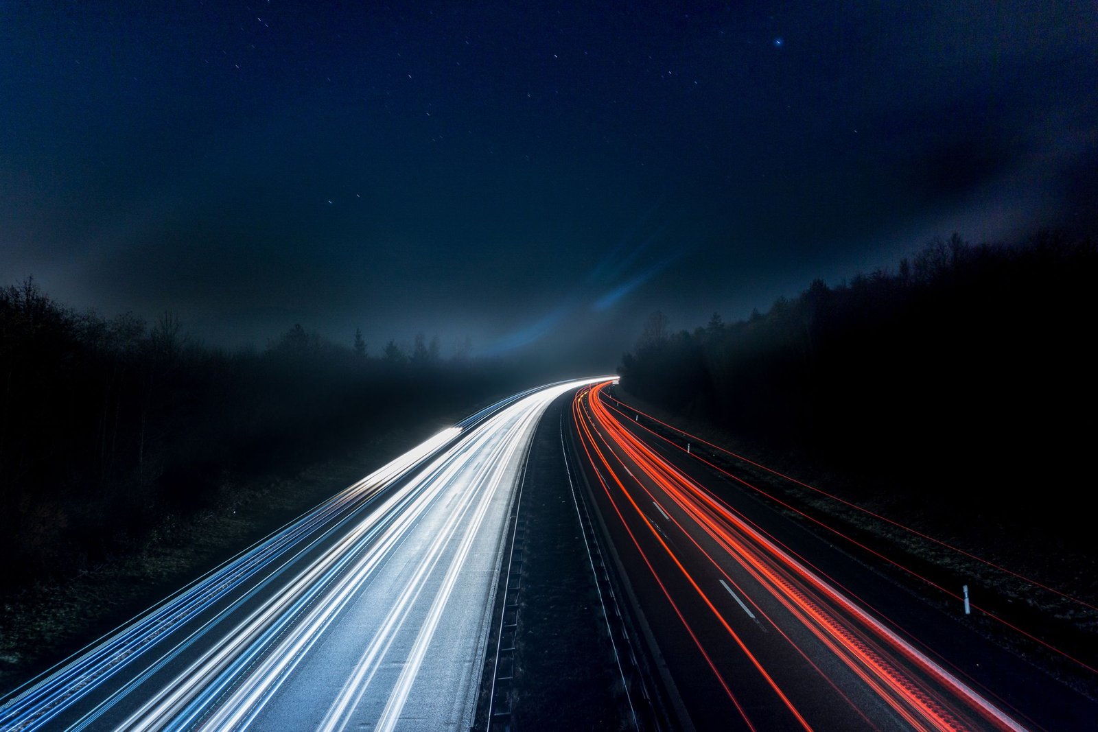 A Saudi city highway at dusk, with light trails from traffic and a skyline beyond