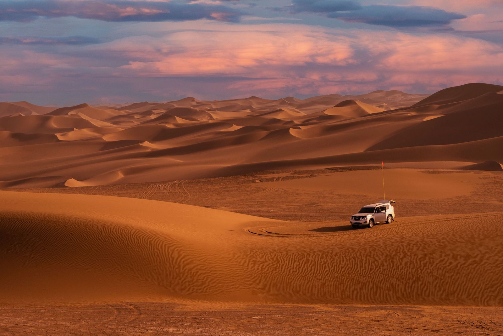 A sports car on an empty desert road in low sunlight