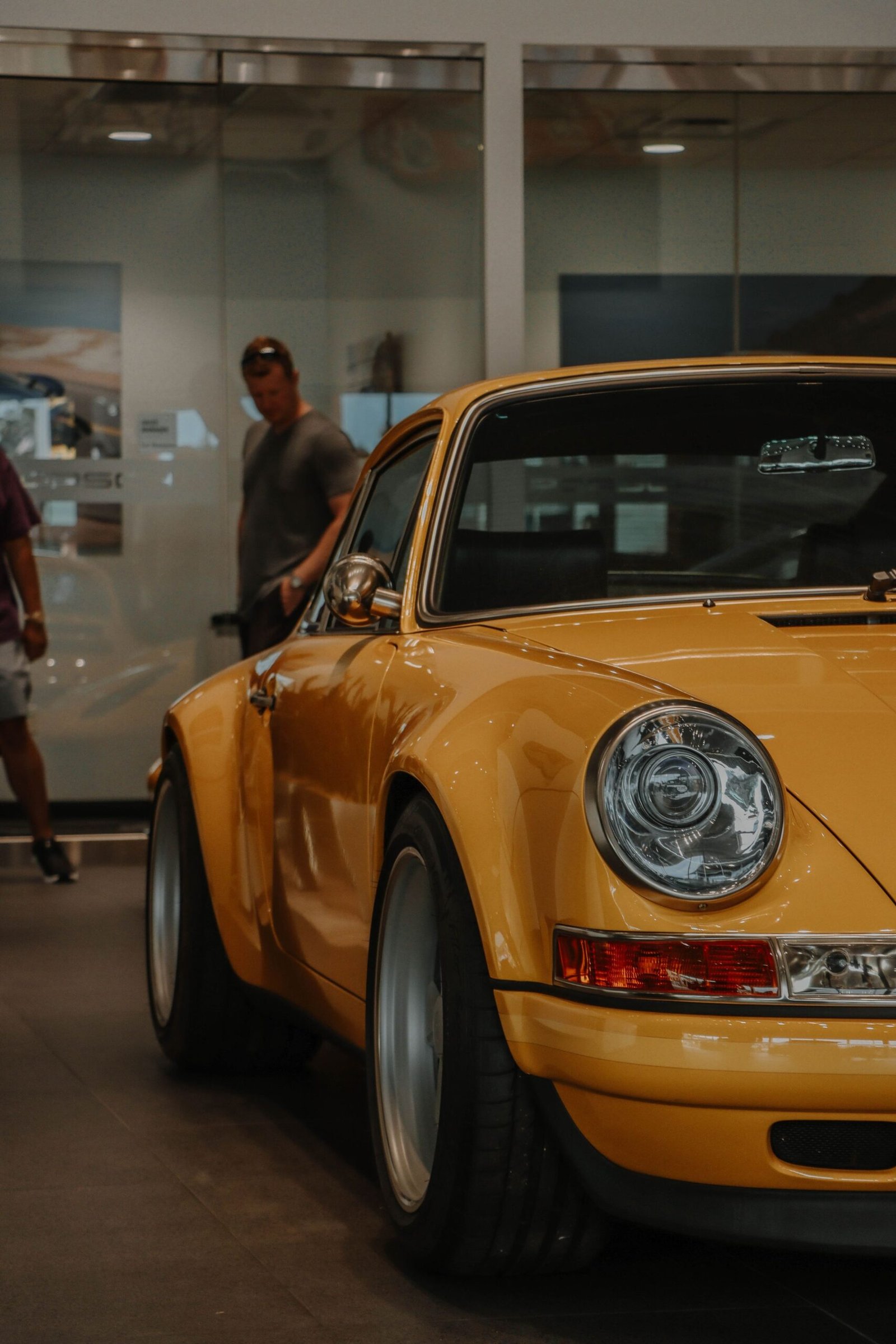 A classic sports car lit by spotlights in a darkened hall