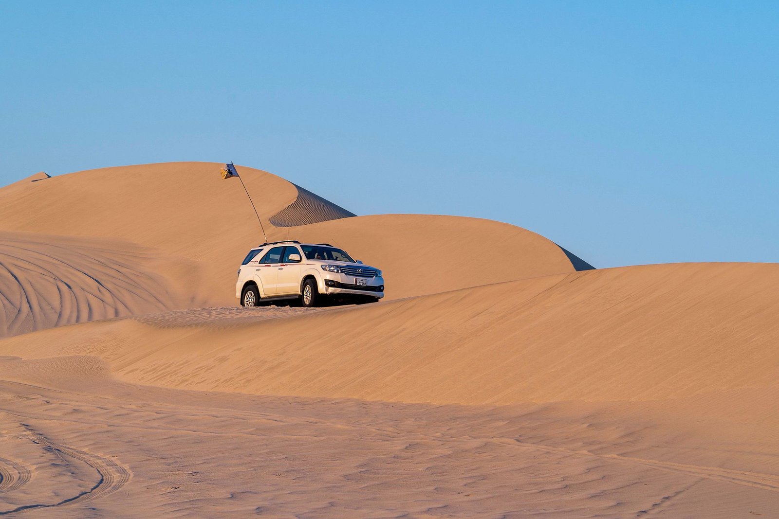 An SUV driving across soft sand dunes