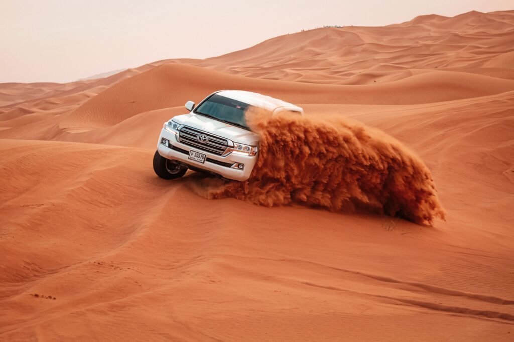 A vehicle on the crest of a dune with the desert beyond