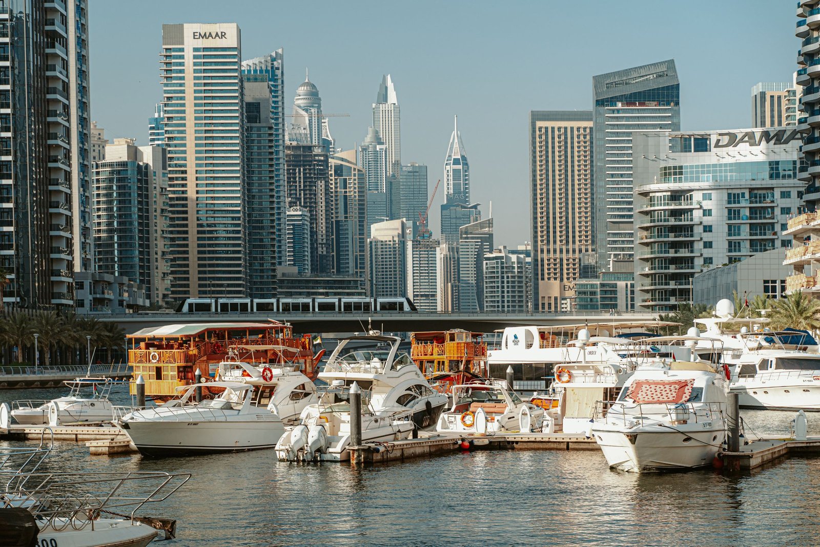 Yachts moored in a marina with a city skyline behind