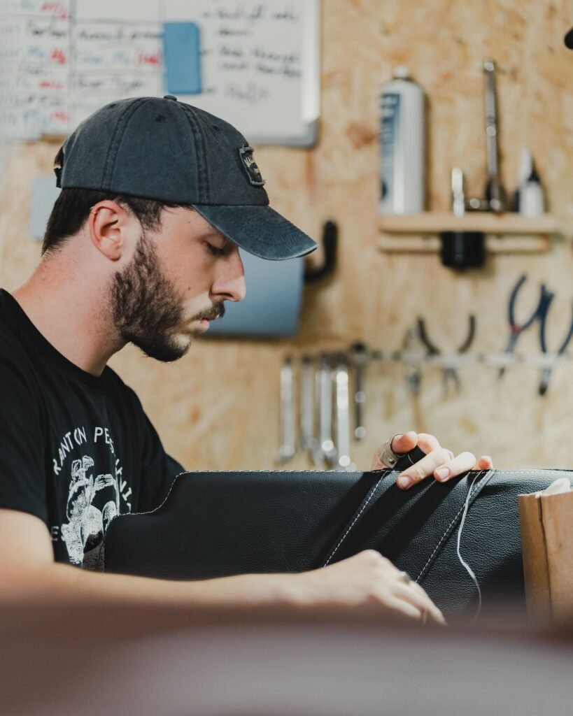 A leather handbag being stitched on a craftsman's workbench