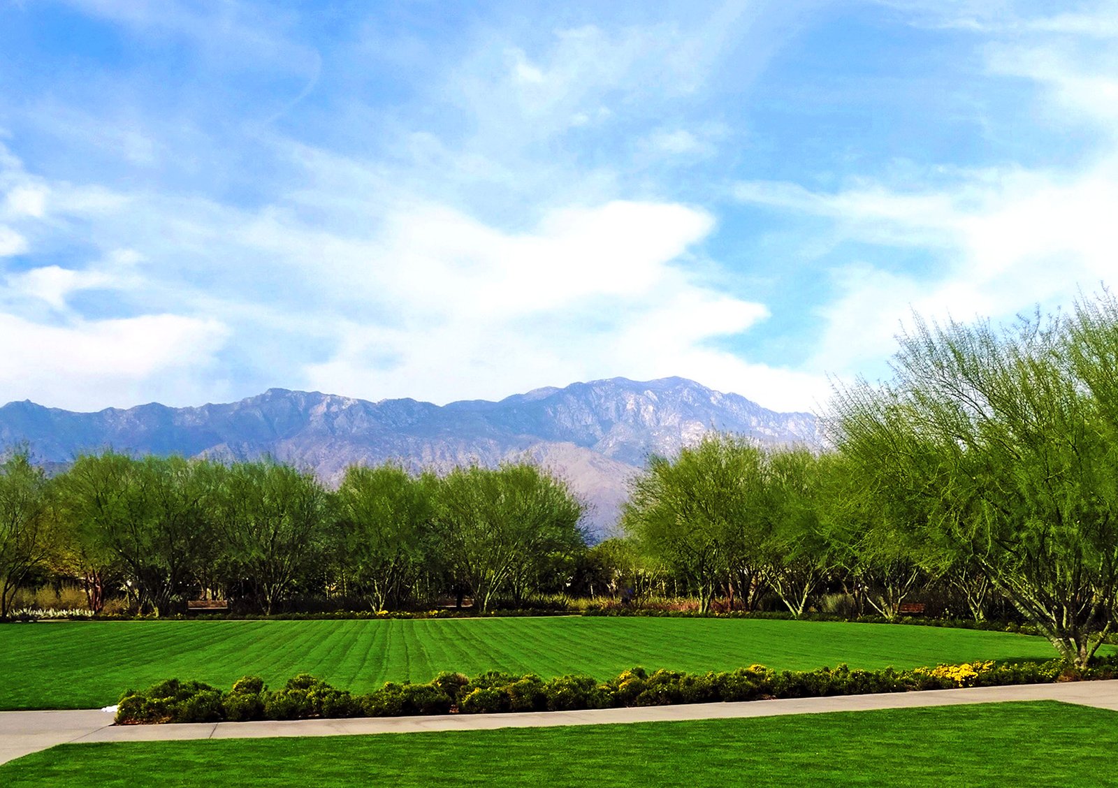 A green golf fairway with bare mountains behind under a clear sky