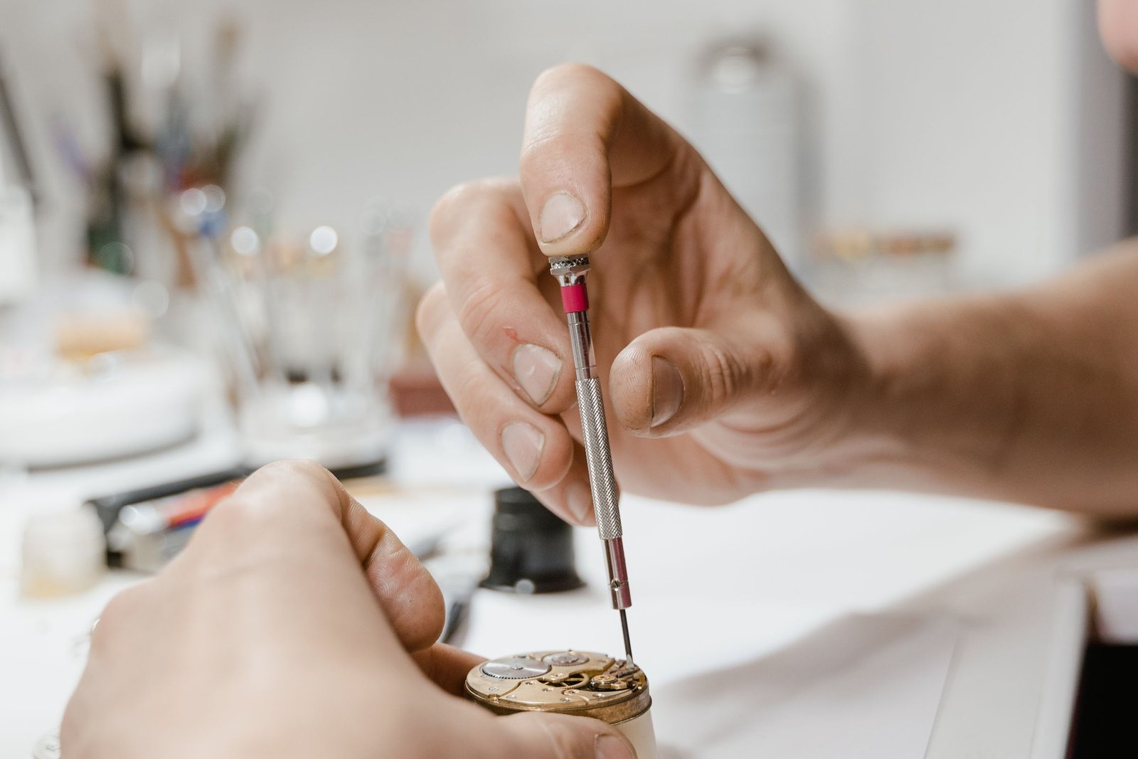 Hands using a fine screwdriver on an open wristwatch