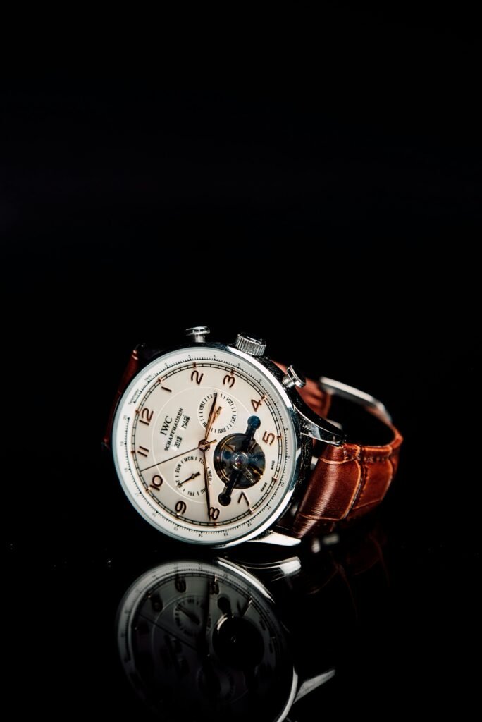 A steel chronograph with sub-dials and a brown leather strap, reflected in a mirror
