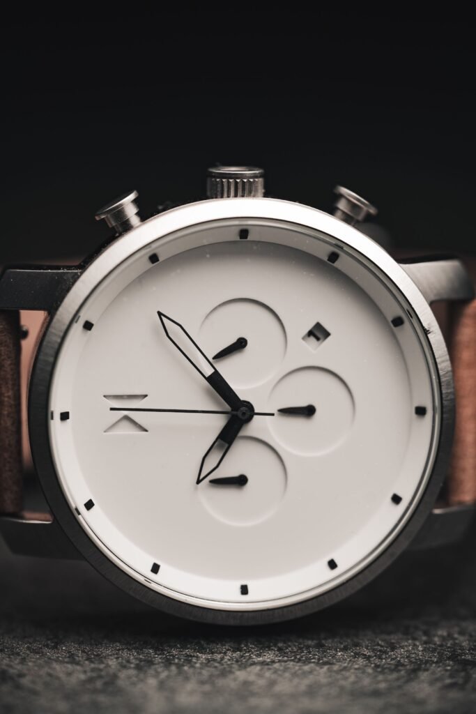 A minimalist watch with a white dial and a leather strap