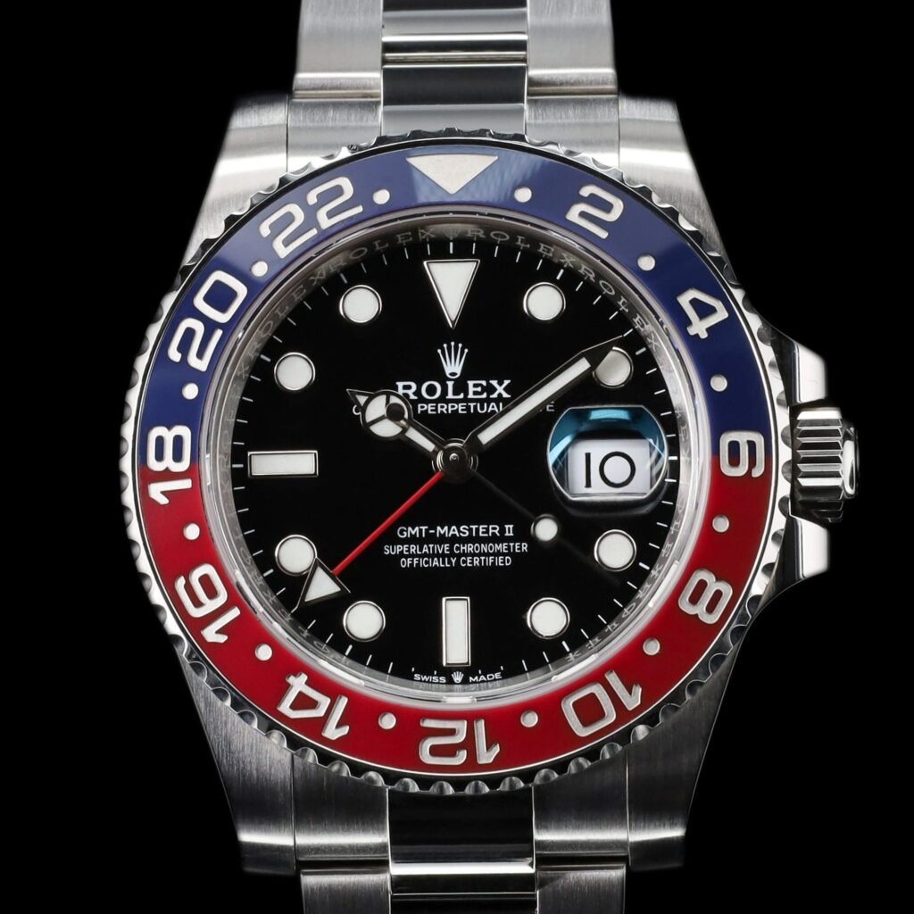 A steel GMT watch with a black dial and a red and blue bezel