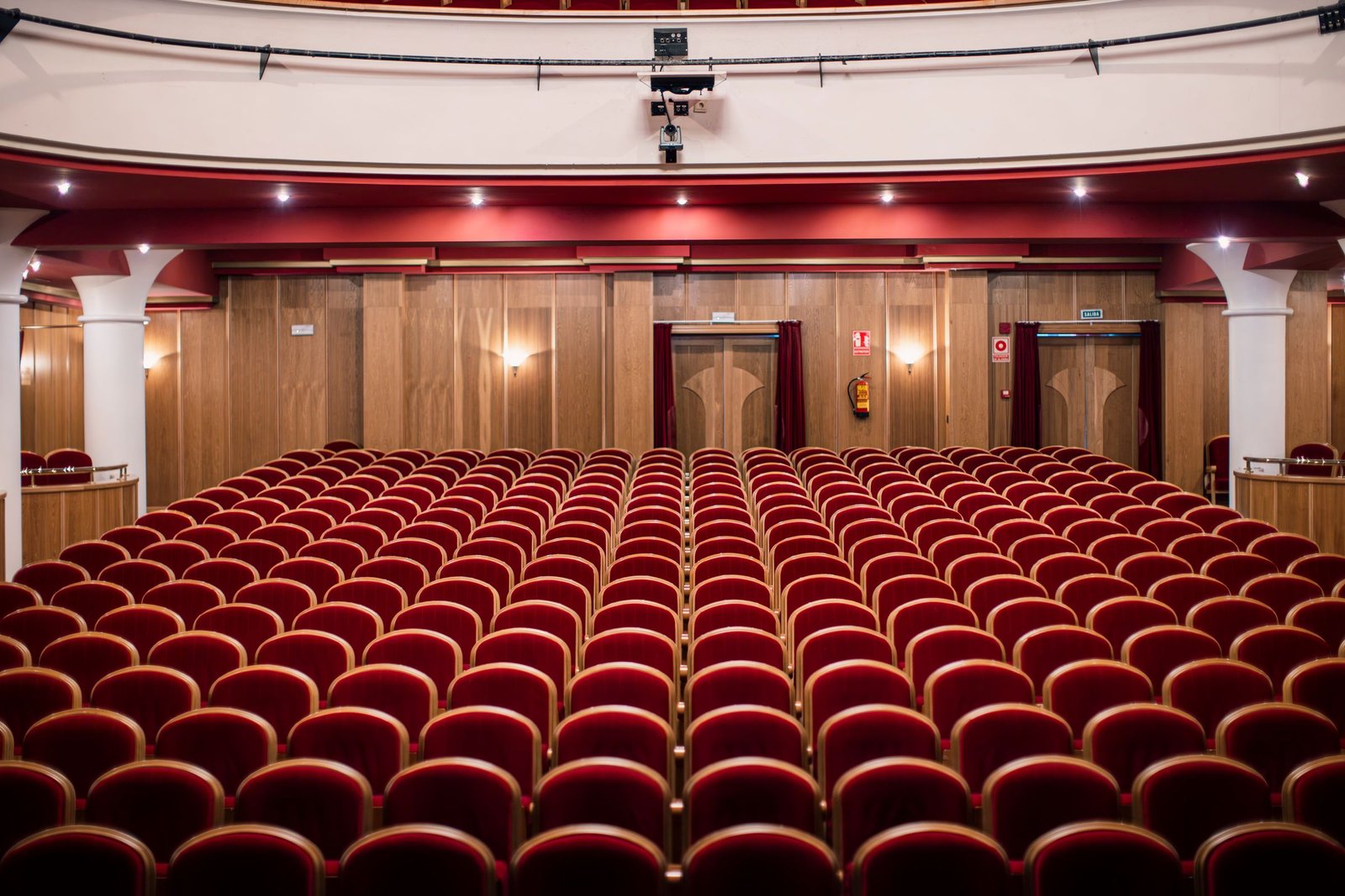 An empty auditorium with rows of seats facing a lit stage