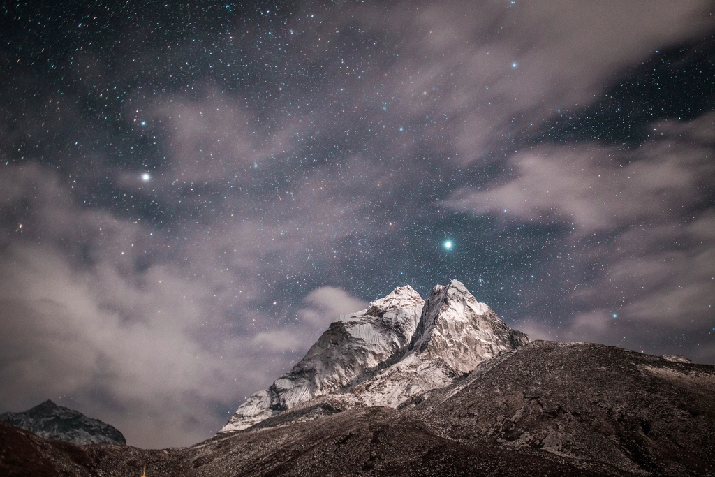 A clear night sky full of stars above dark mountain peaks