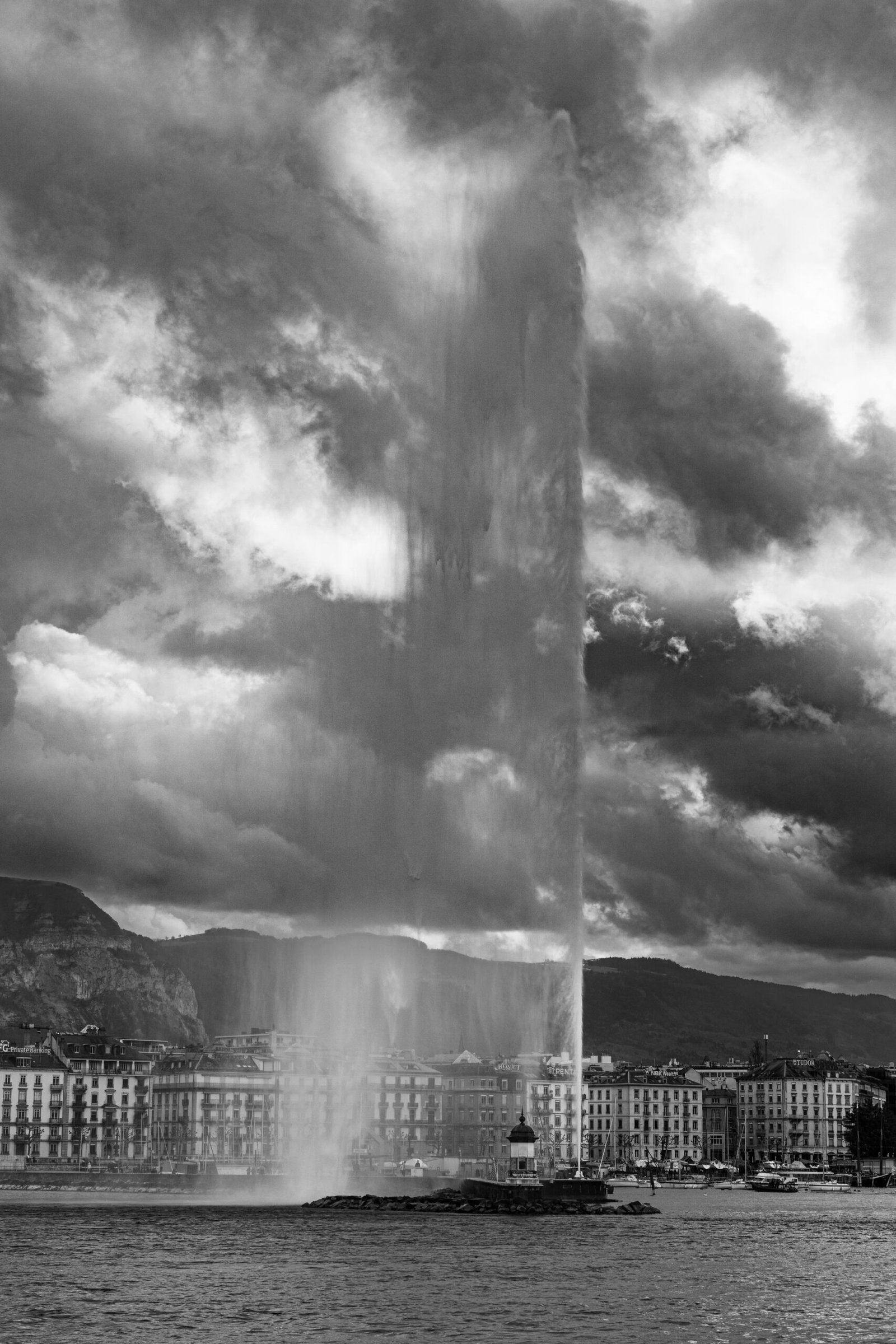 The Jet d’Eau fountain rising over Lake Geneva at dusk, with lights along the shore