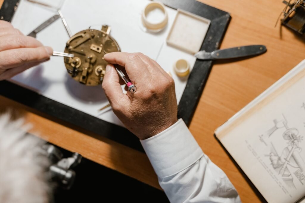 Watchmaking tools and watch parts laid out on a wooden workbench