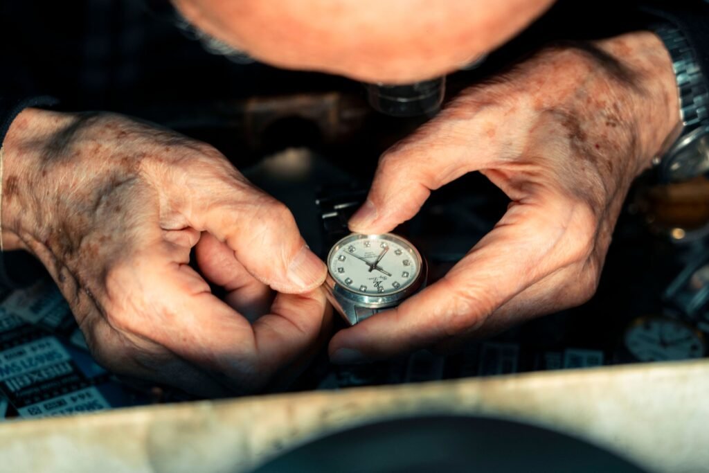 A watchmaker's hands working on a wristwatch under magnification
