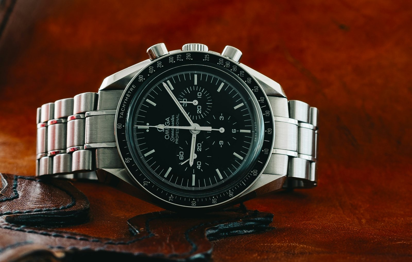 An Omega Speedmaster Moonwatch with a black dial and tachymeter bezel