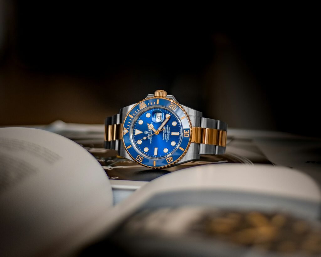 A two-tone Submariner with a blue dial and blue bezel resting on an open book